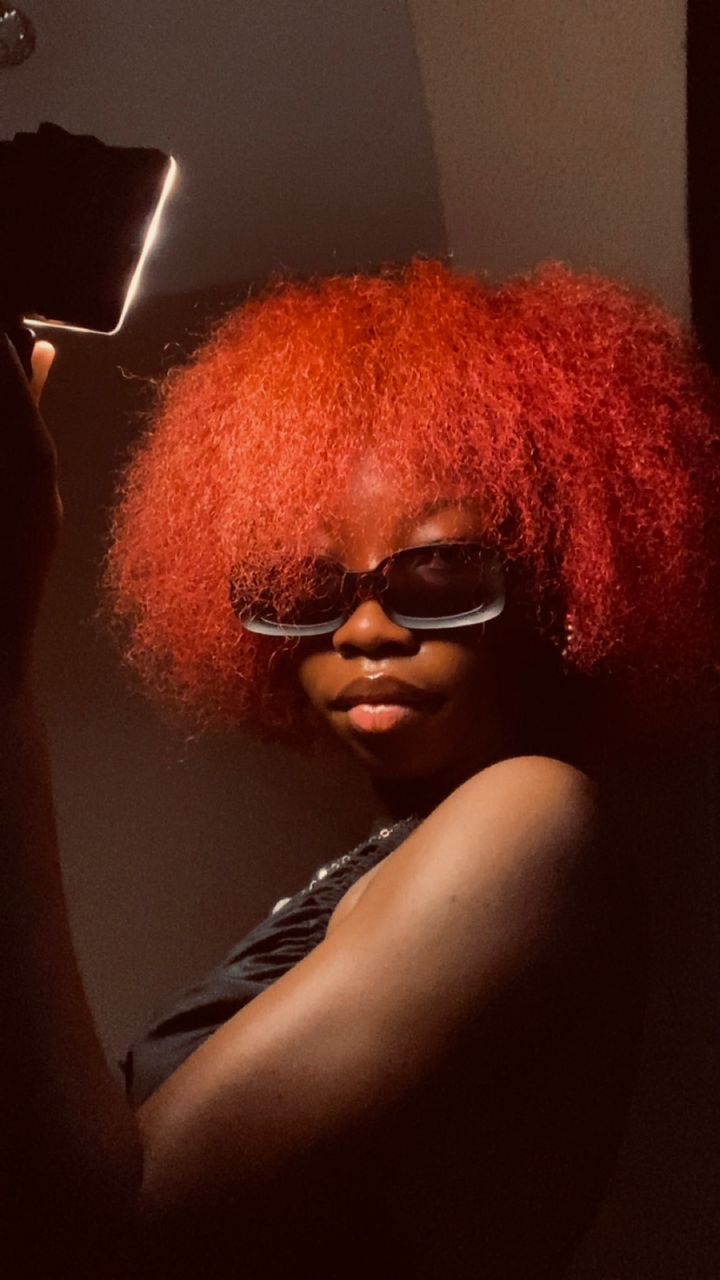 Abby with her red afro in moody light