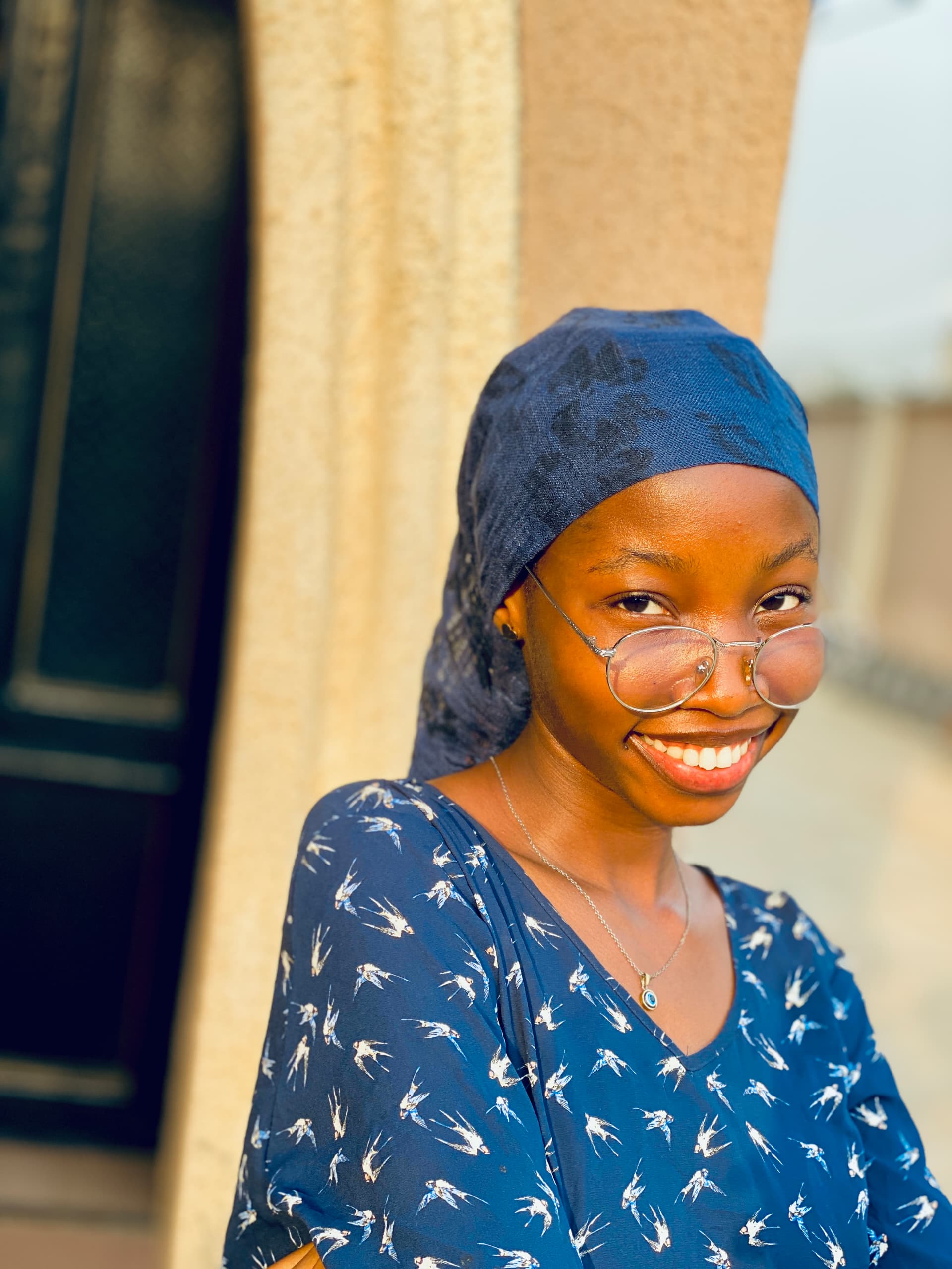 Abby beaming in her blue headscarf and glasses